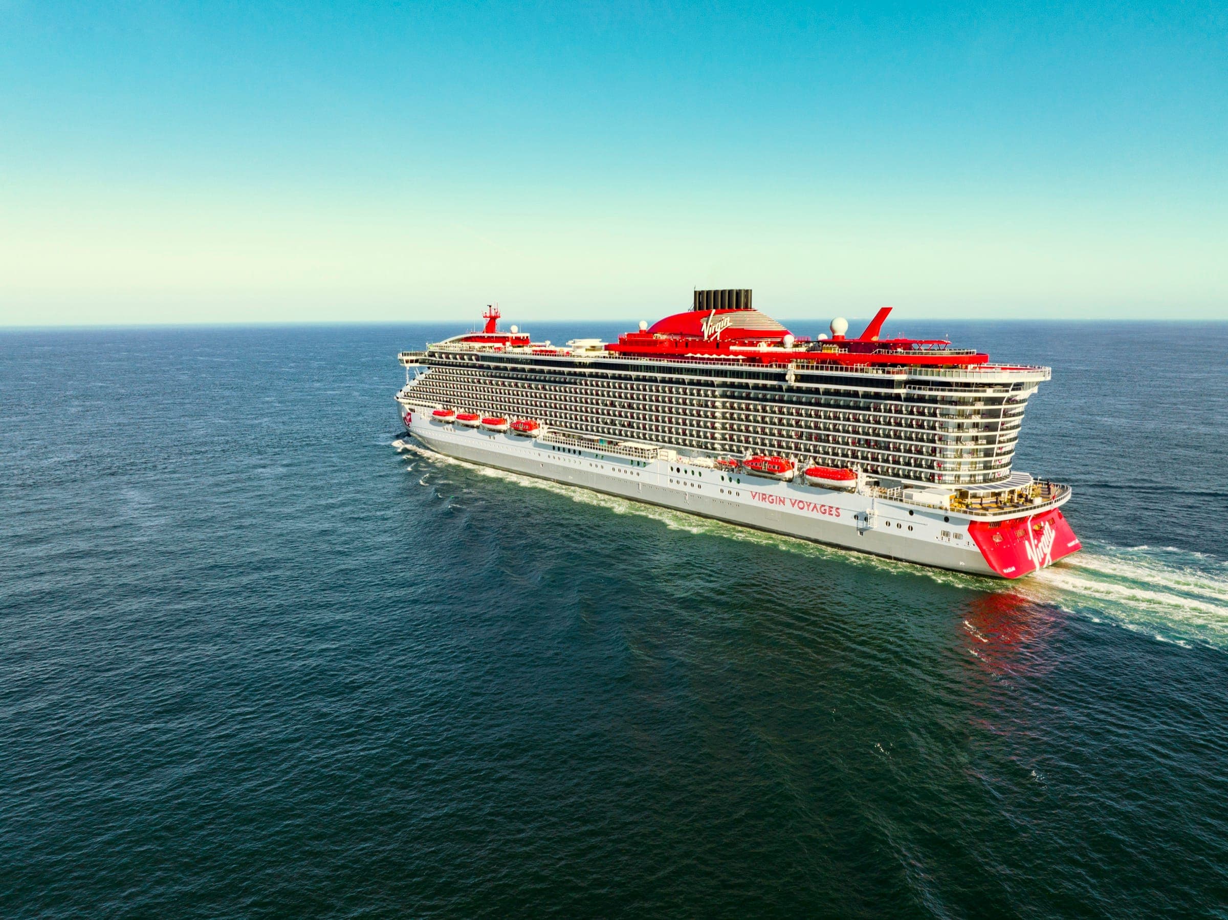 Virgin Voyages ship sailing at sunset