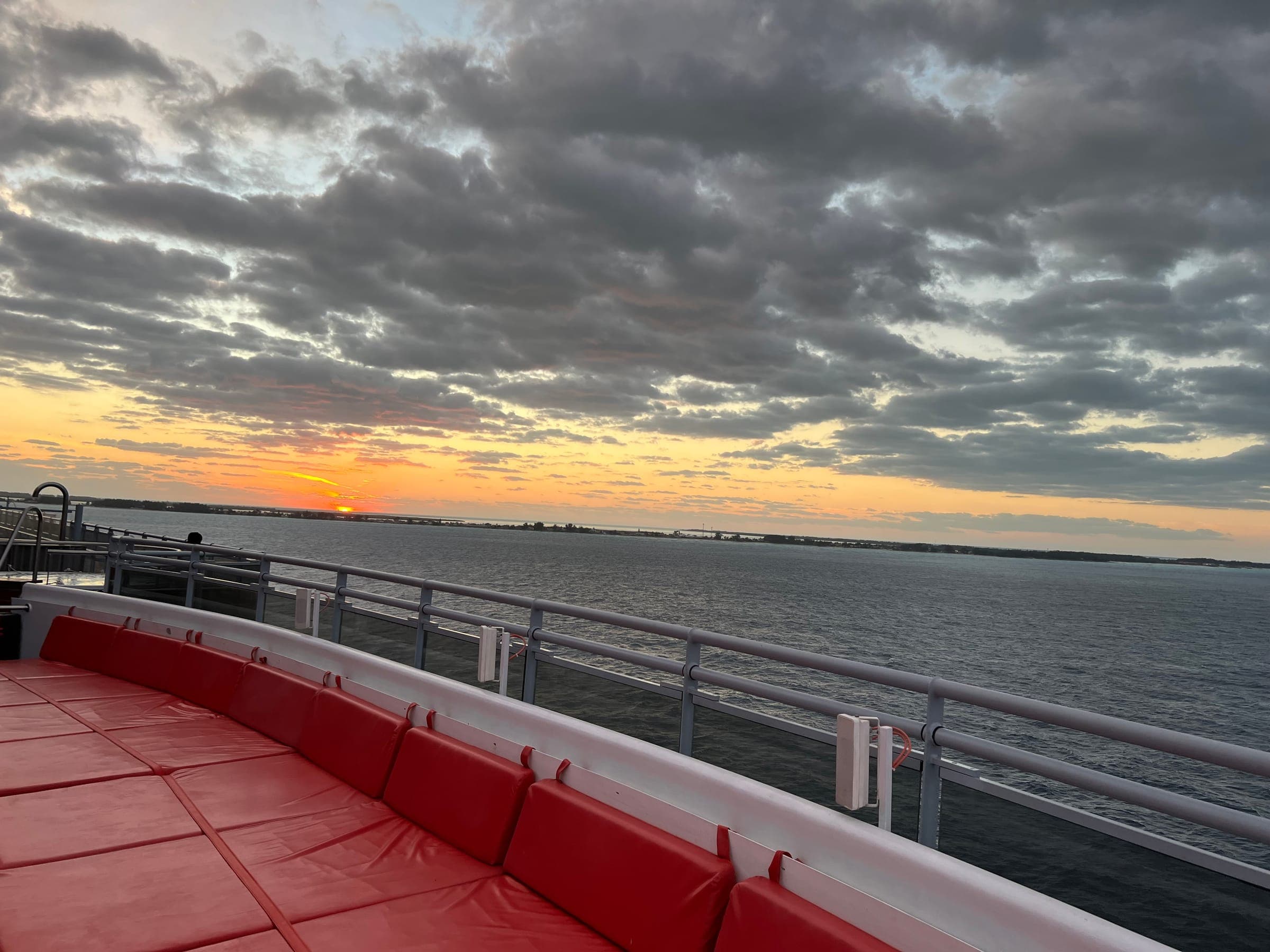 Red cushioned lounge chairs on deck at sunset